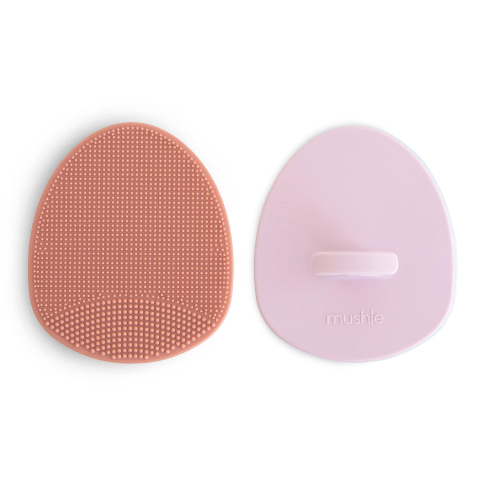 Brosse Mushie bébé en silicone rose, massage doux et élimination des croûtes.