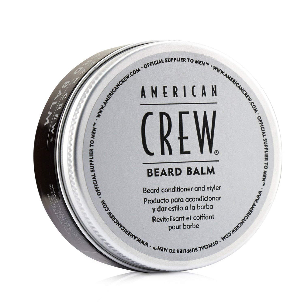 Les mains appliquant le baume barbe American Crew pour un coiffage souple.