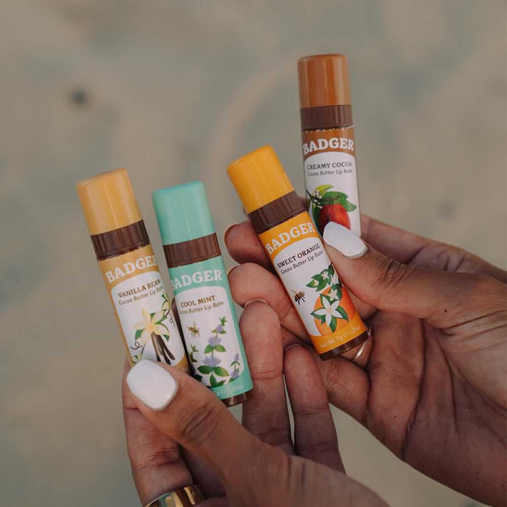 Hand holding Badger lip balm for lip moisture in dry weather.