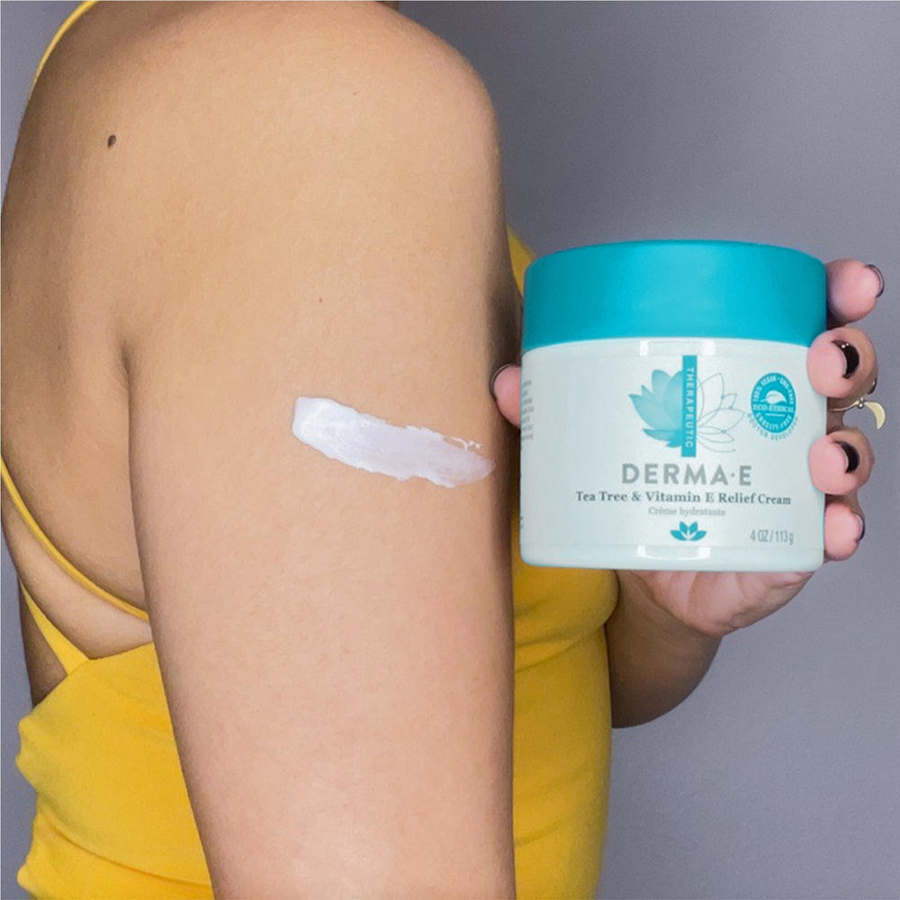 Crème Derma E appliquée sur coudes et genoux, hydratation ciblée.