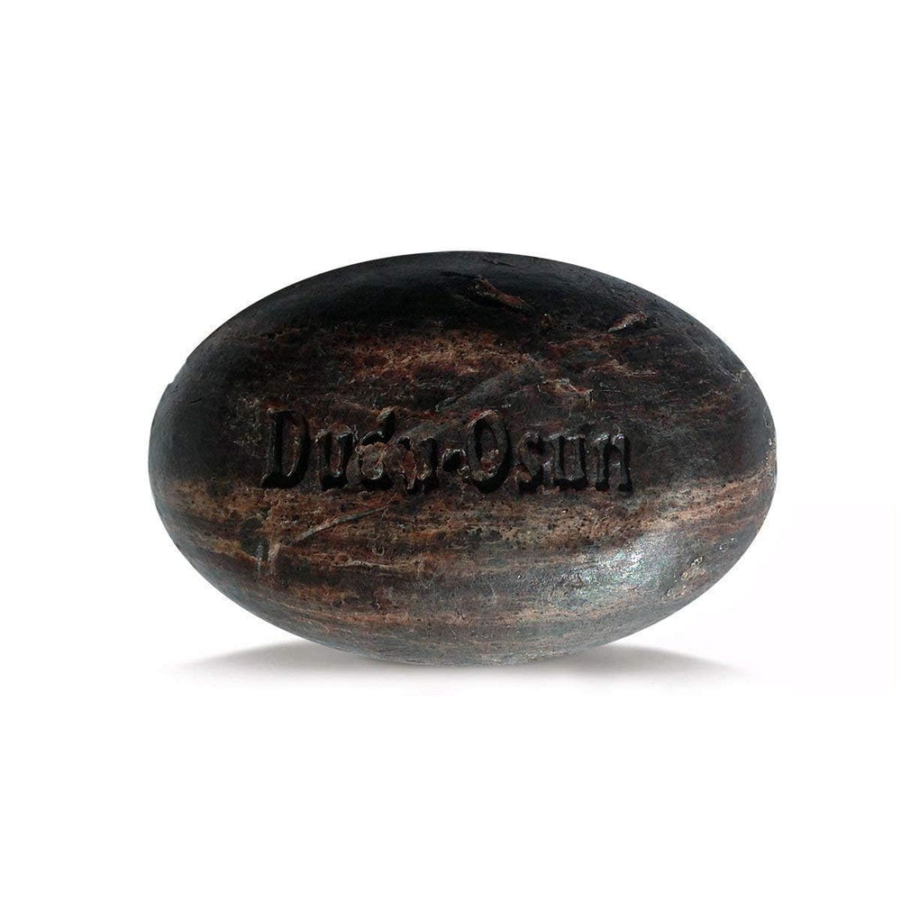 Savon noir africain Dudu-Osun en main, mousse riche pour nettoyage en douceur.