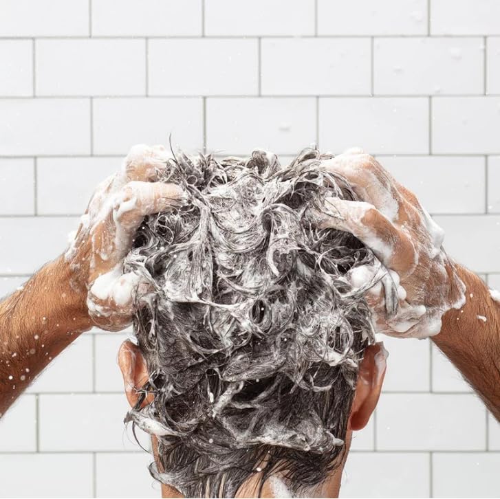 Homme utilisant le soin, cheveux plus souples et brillants