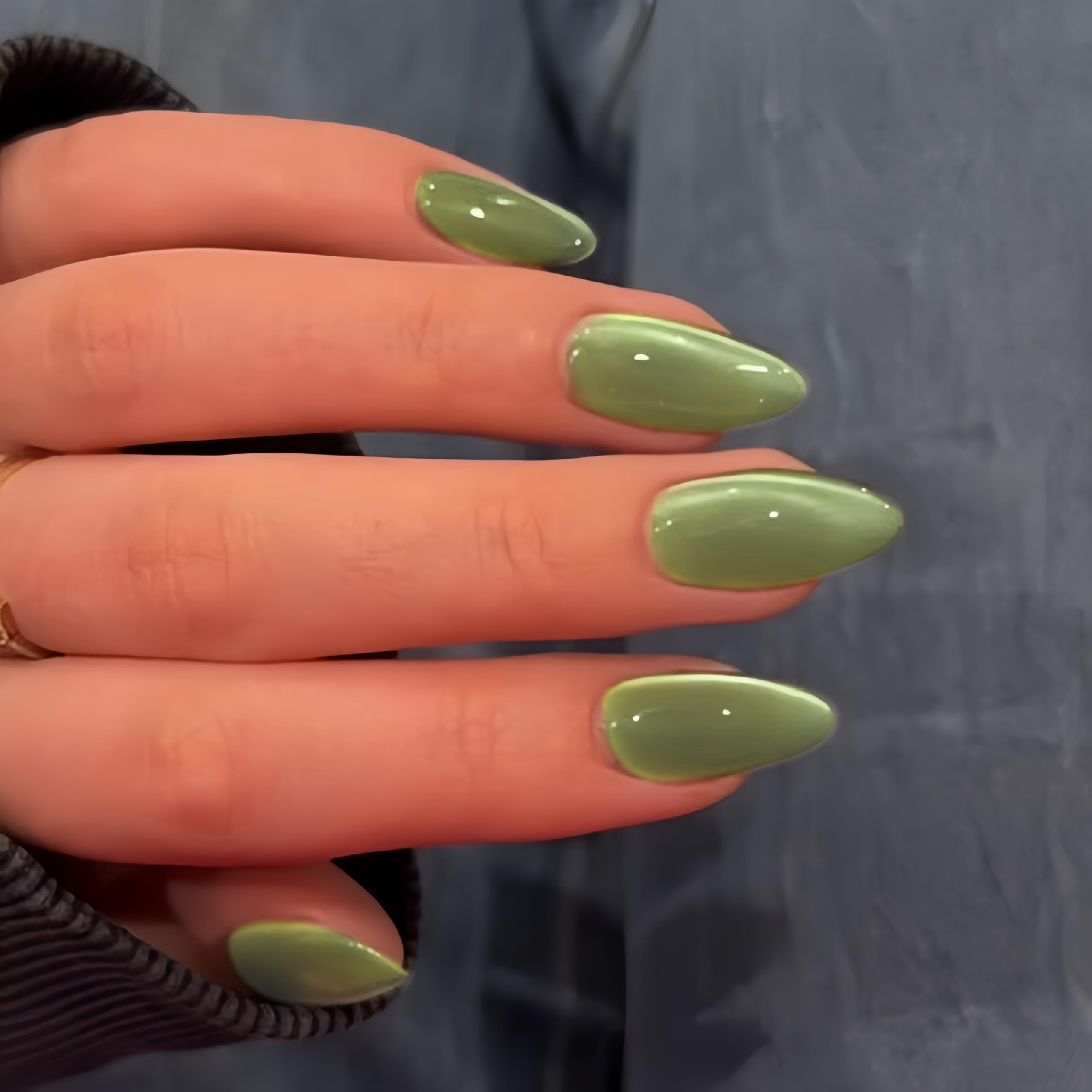 Gros plan sur les ongles KQueenest avec effet oeil-de-chat vert sauge, brillance durable.