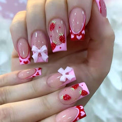 Ongles Lomxene Valentine avec nœud et fraise, manucure romantique et rapide.