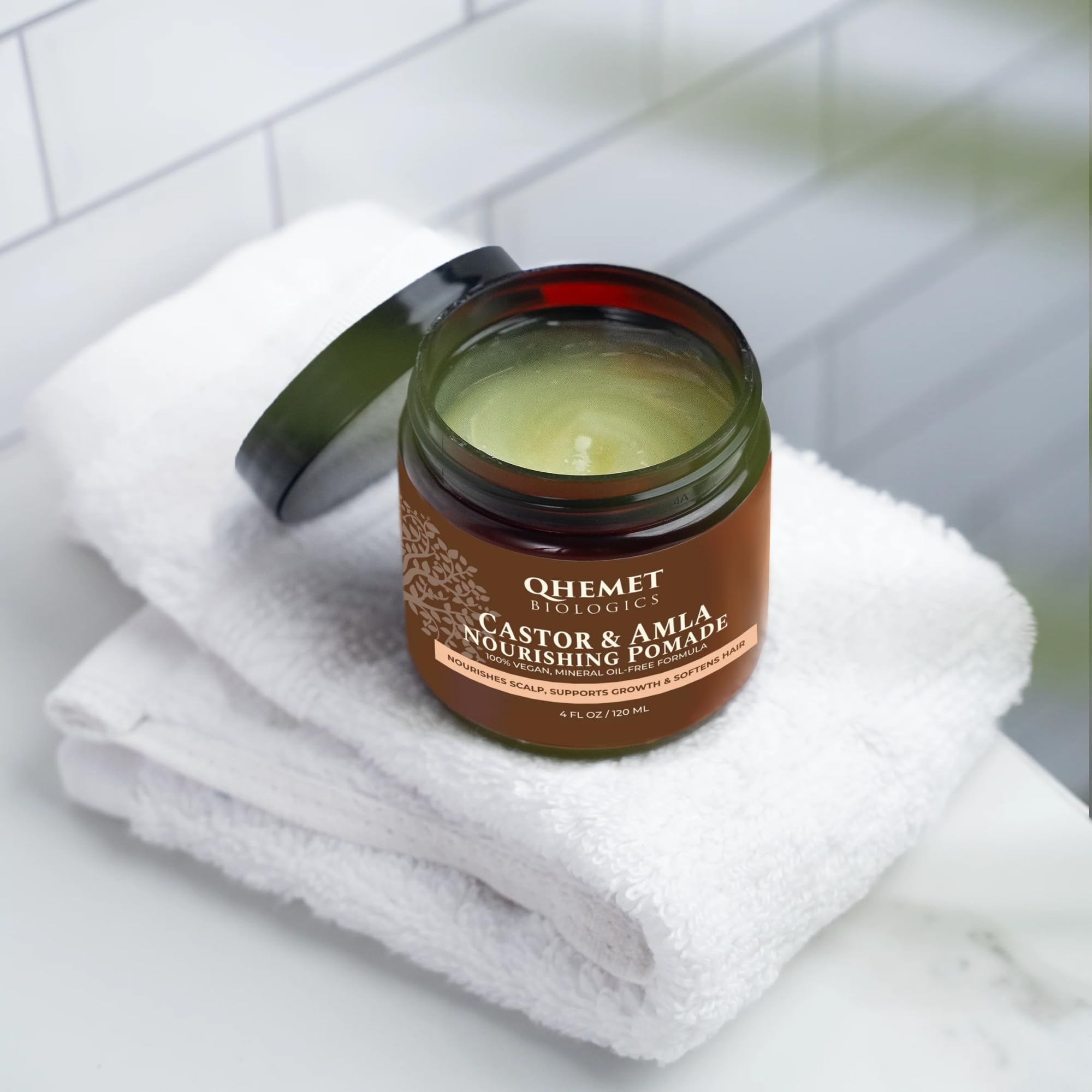 Qhemet Biologics Castor and Amla pomade texture being smoothed into hair for pliability.